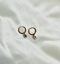 Pair of gold hoop earrings with small pearls on a white fabric background