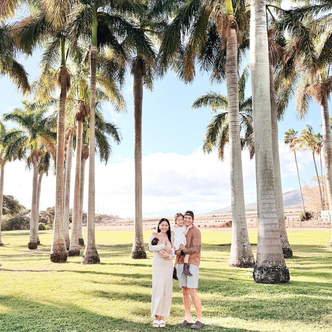 a family of four standing together in front of palm trees