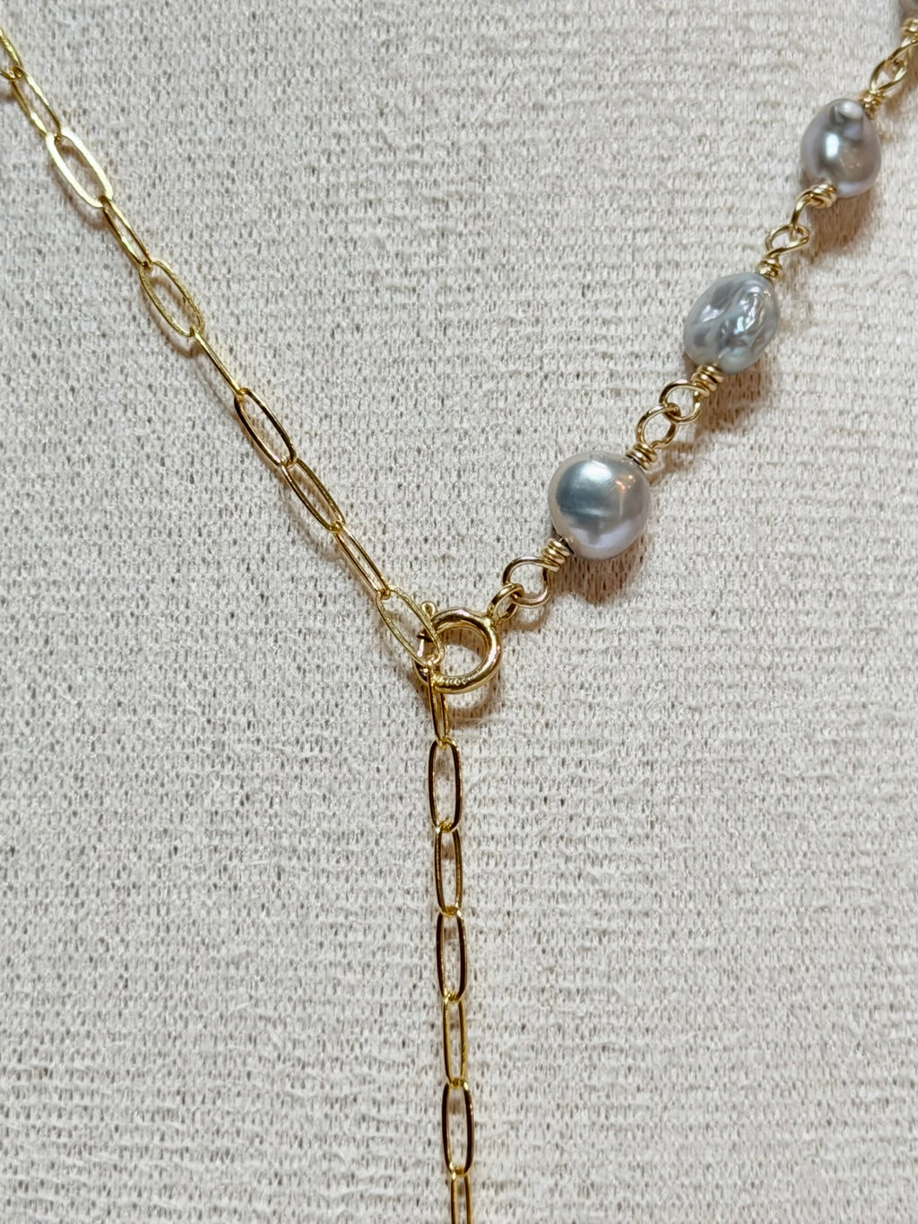 Close-up detail of Pau'ole necklace showing gray keshi pearls wire-wrapped along gold chain meeting at front clasp