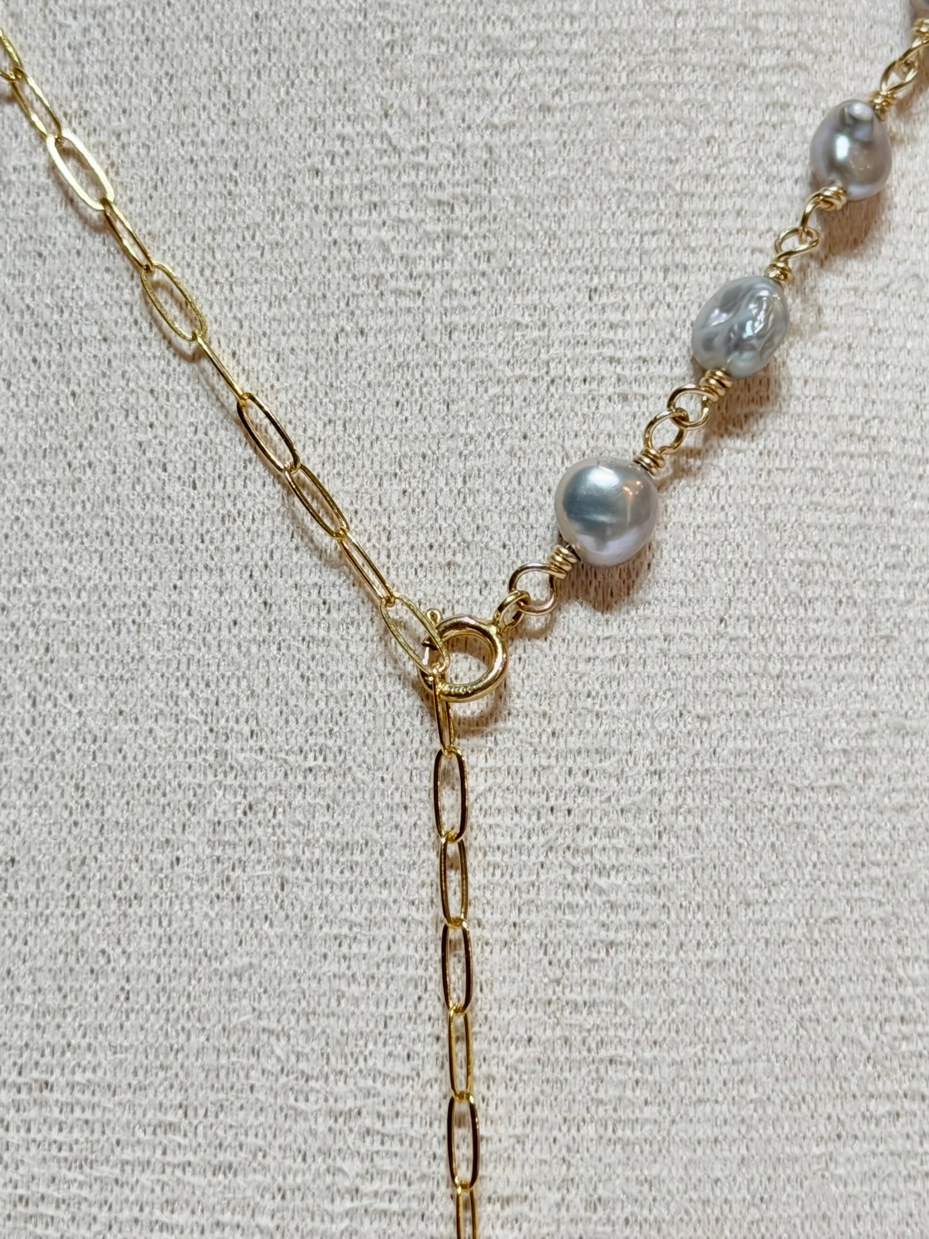 Close-up detail of Pau'ole necklace showing gray keshi pearls wire-wrapped along gold chain meeting at front clasp